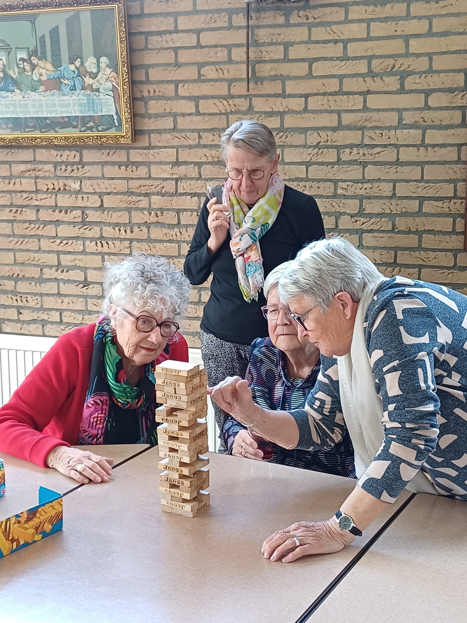 Drie oudere dames spelen samen een spelletje Jenga in een van de zalen van de kerk in Midwolda. Een vierde dame kijkt gespannen toe.
